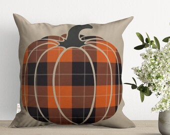 May include: A beige throw pillow with a black and orange plaid pumpkin design.