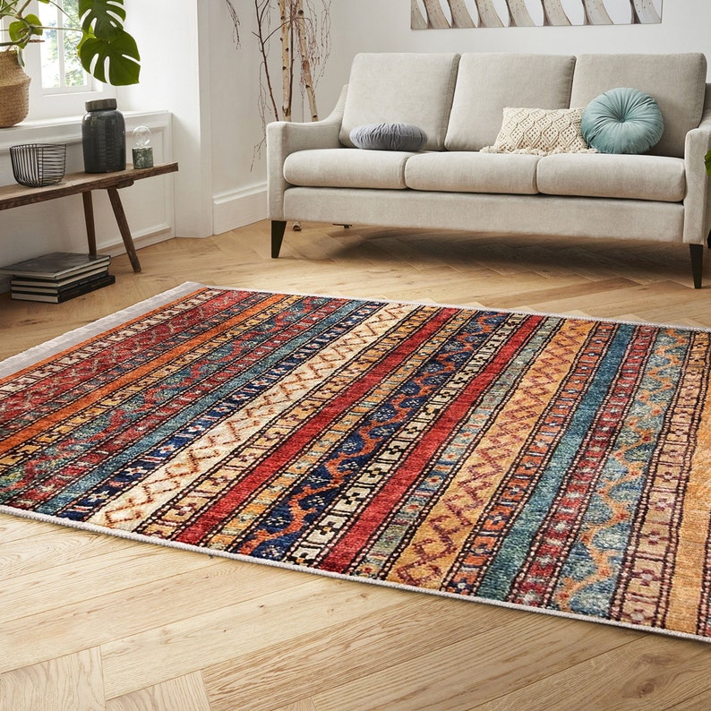 Hereke Motif Rug-A colorful, striped rug with a geometric pattern in shades of red, orange, blue, and yellow. The rug has a fringe border.