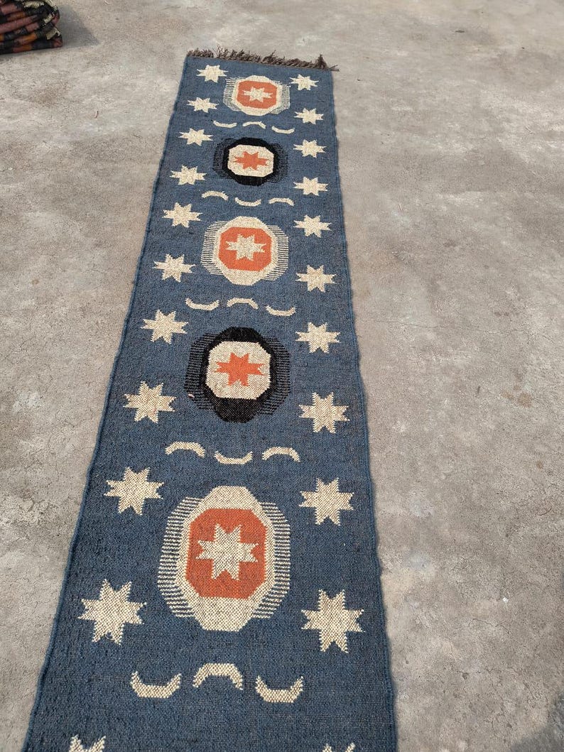 May include: A blue and white runner rug with a geometric pattern of stars and circles. The circles have a red and orange center.