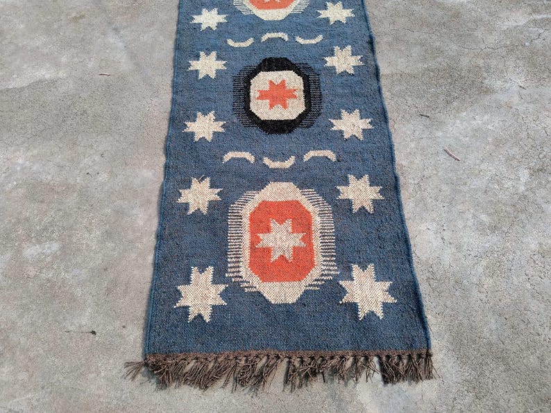 May include: A blue and orange patterned rug with a fringe border. The rug has a geometric design with stars and circles.