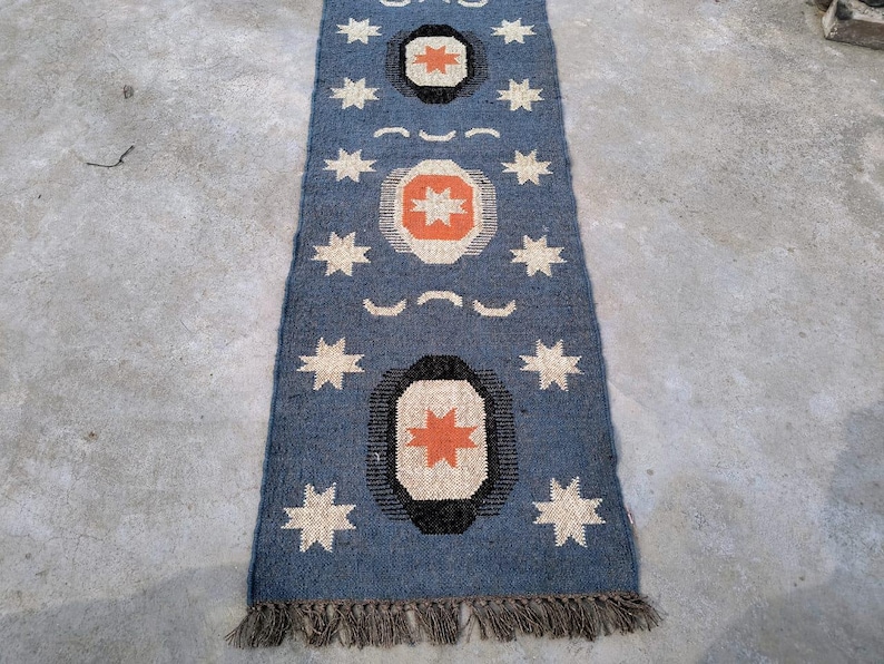 May include: A blue and orange patterned rug with a fringe border. The rug has a geometric design with stars and circles.