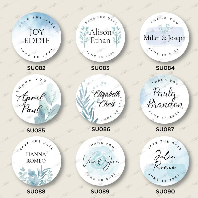 Op de afbeelding: Negen ronde blauwe en witte stickers voor een huwelijksdatum met aquarelontwerpen en kalligrafietekst. De tekst bevat de namen van de stellen en de datum van de bruiloft. De stickers zijn gelabeld met de productcode SU082 tot en met SU090.