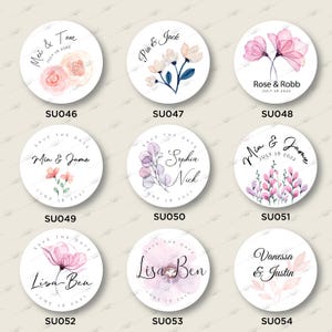 Op de afbeelding: Set van 10 ronde 'Save the Date'-stickers met bloemenmotieven en trouwdetails. De stickers tonen verschillende bloemstukken in roze, paarse en blauwe tinten, met tekst die de namen van de paren, de trouwdatum en de zin 'Save the Date' bevat.