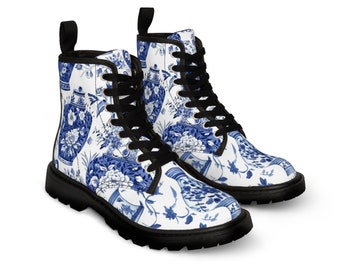 Puede incluir: Un par de botines con base blanca y estampado floral azul que representa jarrones y tarros de jengibre tradicionales. Las botas tienen cordones negros, ojales metálicos negros, tiradores negros en el talón y suelas de goma gruesa.