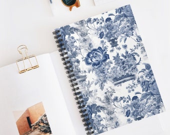 Puede incluir: Una libreta de espiral con fondo blanco y un patrón floral azul y blanco. Las flores son de estilo vintage y están dispuestas en un patrón repetitivo.
