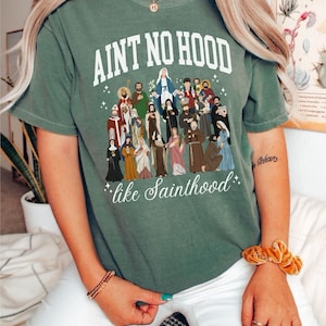 May include: A green t-shirt with the text "Ain't no hood like Sainthood" and a graphic of a group of saints.