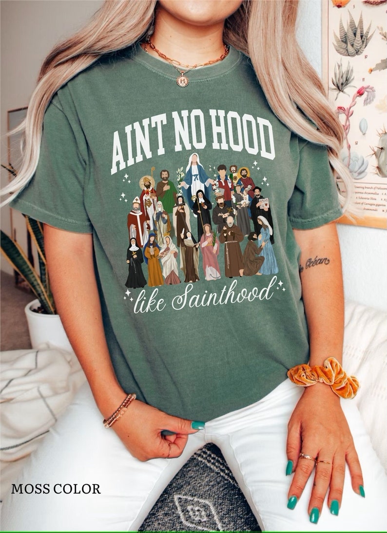 May include: A green t-shirt with the text "Ain't no hood like Sainthood" and a graphic of a group of saints.