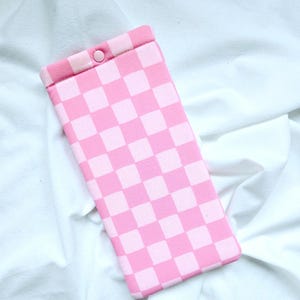 Puede incluir: Funda para tel&eacute;fono de cuadros rosa y blancos con cierre a presi&oacute;n.