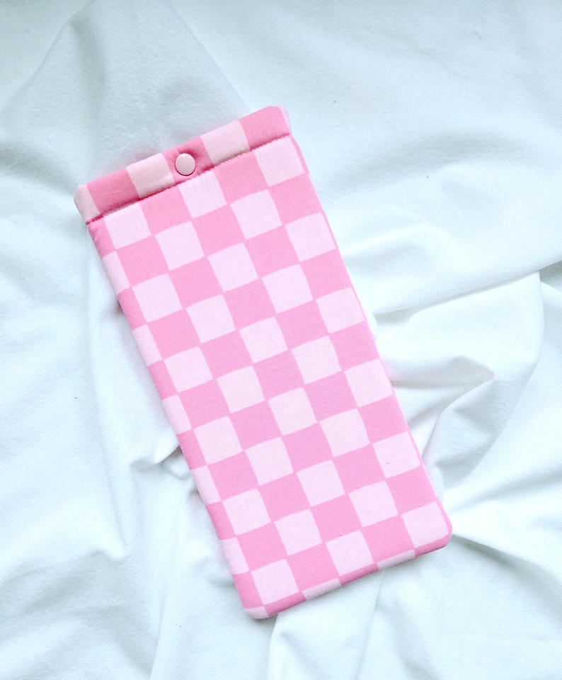 Puede incluir: Funda para tel&eacute;fono de cuadros rosa y blancos con cierre a presi&oacute;n.