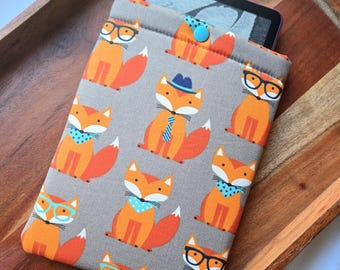 May include: A gray and orange fabric e-reader case with a pattern of foxes wearing glasses and ties. The case has a blue button closure.