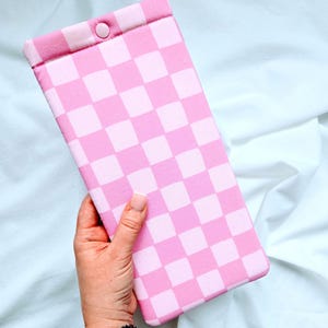 Puede incluir: Bolsa de tela a cuadros rosa y blanca con cierre de presi&oacute;n.