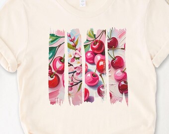 May include: A cream colored t-shirt with a graphic print of pink and red cherries with white blossoms on a pink and white background.