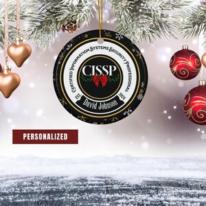May include: A black and gold Christmas ornament with a white circle in the center that says "CISSP" with a red bow. The ornament also has the text "Certified Information Systems Security Professional" and "David Johnson" on it.