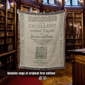 May include: A beige woven tapestry with the text "AN EXCELLENT conceited Tragedie OF Romeo and Juliet."  The text is in a black font and is surrounded by a decorative border. The tapestry is hanging in a library setting.
