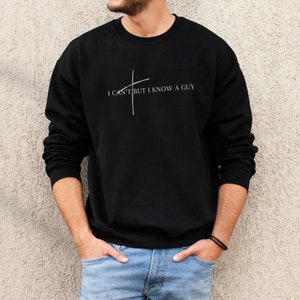 May include: A black sweatshirt with a white graphic that says "I can't but I know a guy" with a stylized cross.