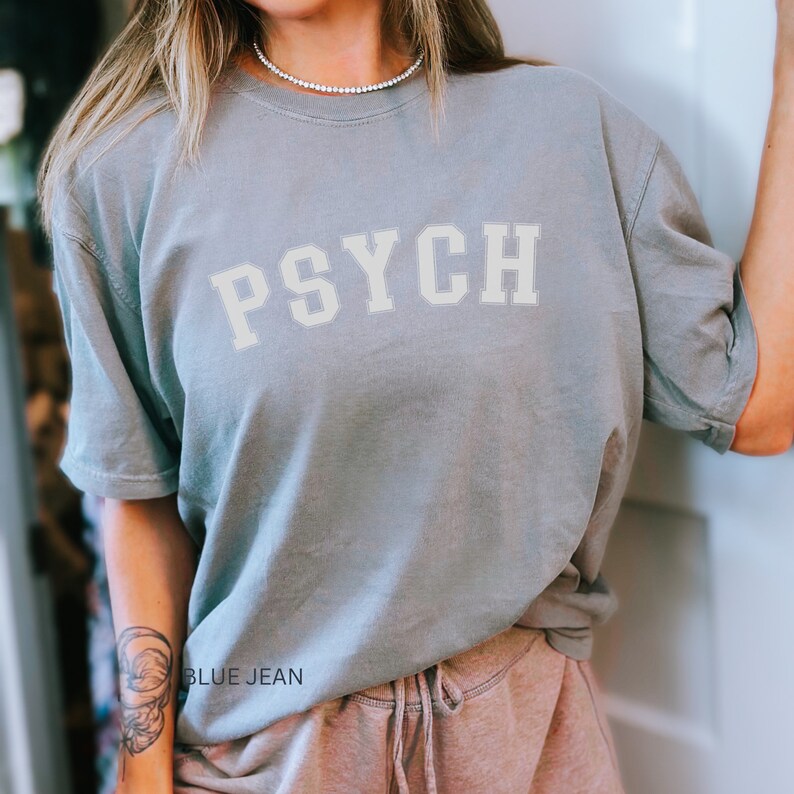 May include: A light blue t-shirt with the word "PSYCH" printed in white on the front. The shirt is made of a soft, comfortable material and has a relaxed fit.
