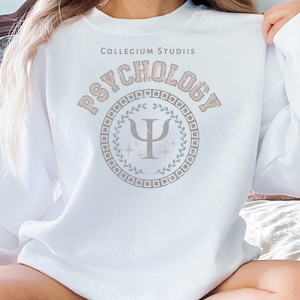 May include: White sweatshirt with the text "Collegium Studiis Psychology" and a stylized Greek letter Psi in a circle with a wreath design.