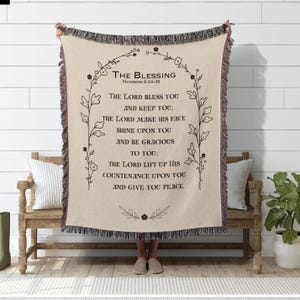 May include: A beige woven throw blanket with a black floral border and the text "The Blessing Numbers 6:24-26" and a bible verse about peace and blessings.