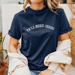 May include: A navy blue t-shirt with the text "Ya'll Need Jesus" in white lettering.