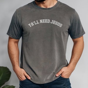 May include: A dark gray t-shirt with the text "Ya'll Need Jesus" printed in white.