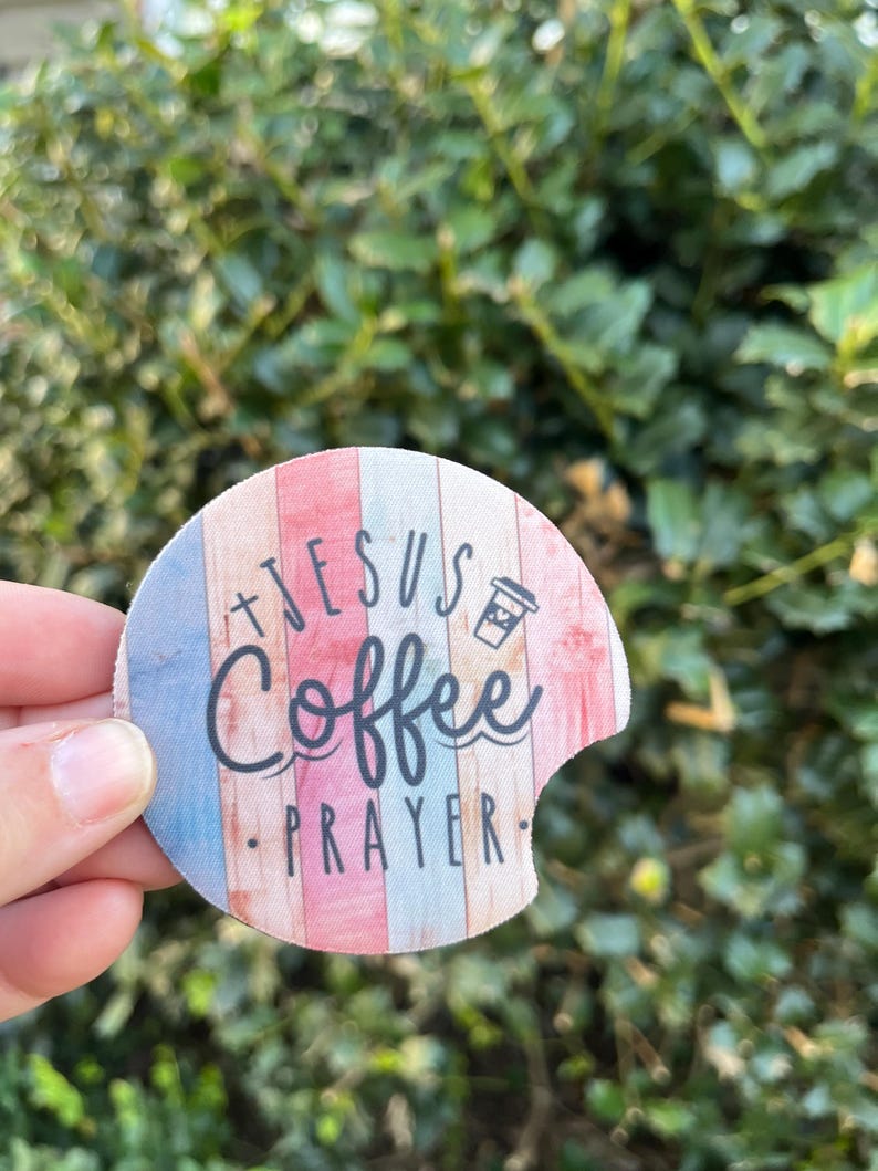 May include: A round, colorful coaster with a woodgrain pattern. It features the text "Jesus Coffee Prayer" and a small coffee cup icon.