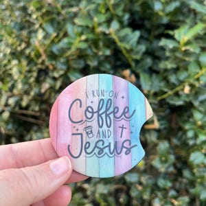 May include: A round, colorful coaster with a woodgrain pattern. The coaster features the text "I run on coffee and Jesus" with a coffee cup icon and a cross.