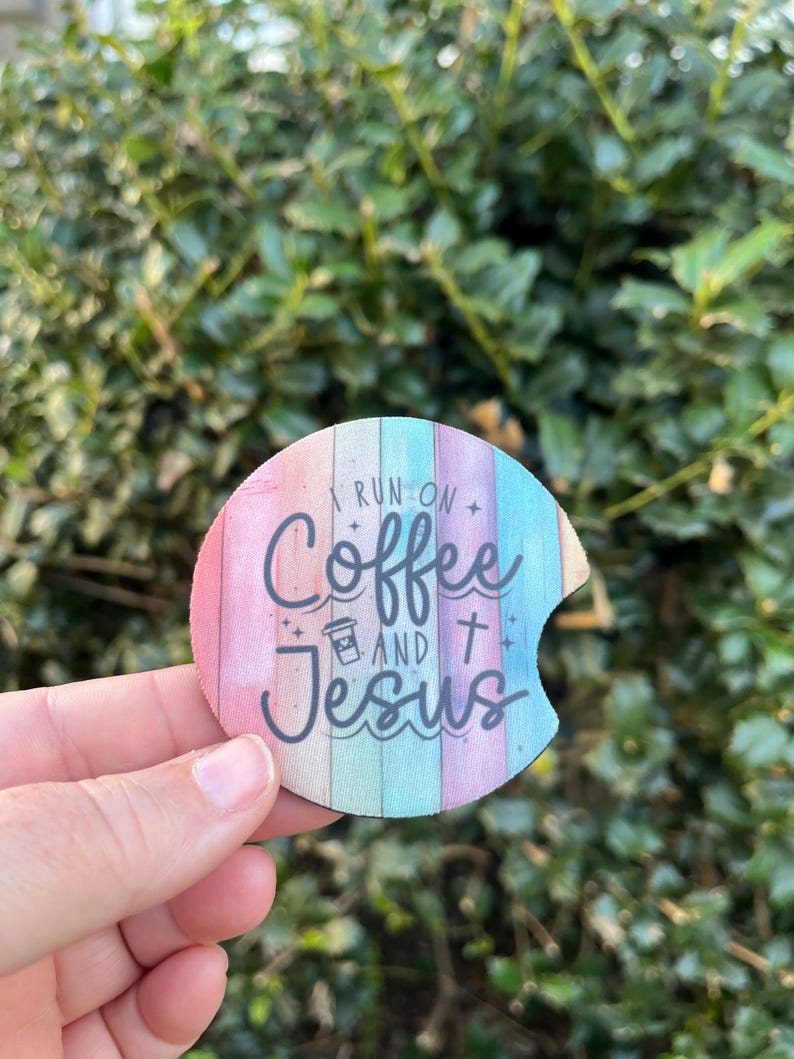 May include: A round, colorful coaster with a woodgrain pattern. The coaster features the text "I run on coffee and Jesus" with a coffee cup icon and a cross.