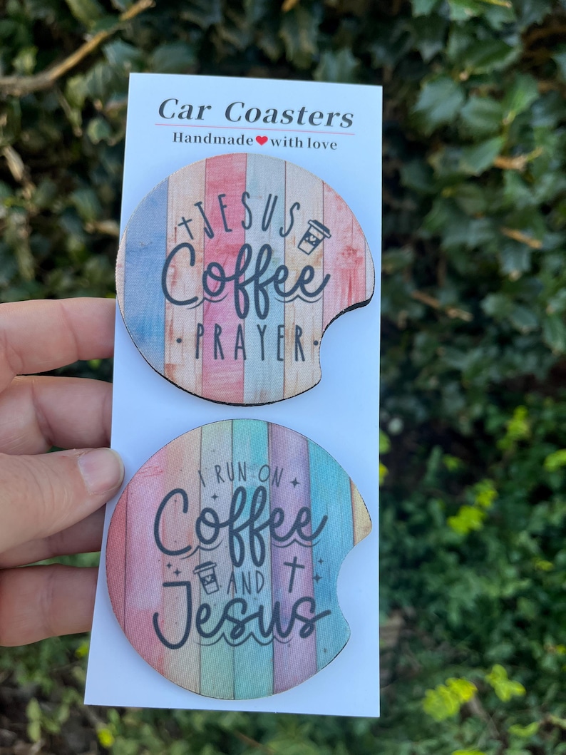 May include: Two round car coasters with a wood grain design. The top coaster features the text "Jesus Coffee Prayer" with a coffee cup icon. The bottom coaster features the text "I run on Coffee and Jesus" with a coffee cup icon and a cross.