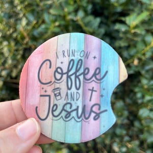 May include: A round, colorful coaster with a rainbow design and the text "I run on coffee and Jesus".