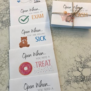 May include: Four white cards with colorful illustrations and the text "Open When..." followed by a reason to open the card. The reasons are "You finish an exam", "You are feeling sick", "You need a treat", and "You need a ...".