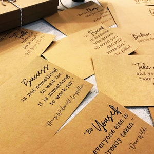 May include: A collection of inspirational quotes printed on brown paper cards. The quotes include "Success is not something to wait for, it is something to work for." - Henry Wadsworth Longfellow, "Be Yourself, everyone else is already taken." - Oscar Wilde, "A friend is someone who knows all about you and still loves you." -  Robert Hubbard, "Be the change that you wish to see in the world." and "Believe you're here for a reason."