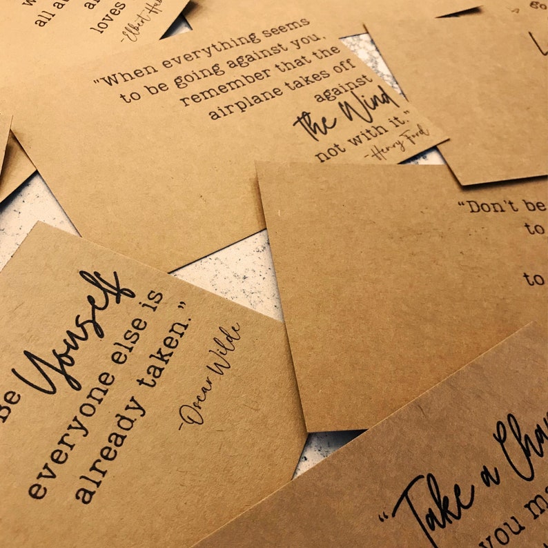 May include: A collection of inspirational quotes printed on brown paper cards. The quotes include "Be yourself, everyone else is already taken." by Oscar Wilde, "When everything seems to be going against you, remember that the airplane takes off against the wind, not with it." by Henry Ford, and "Don't be afraid to give up the good to go for the great."