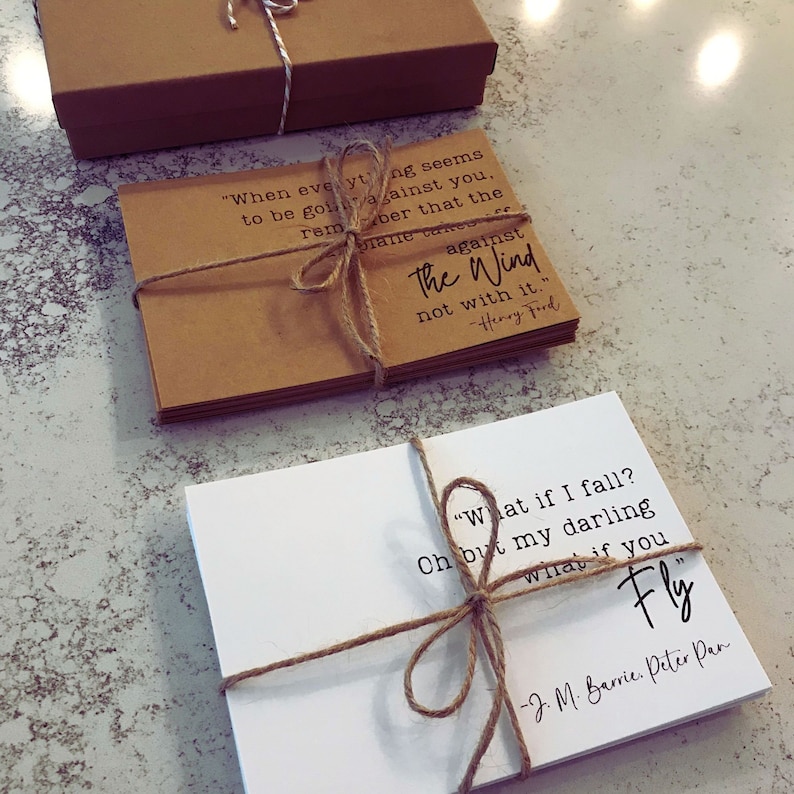 May include: Two sets of inspirational quote cards tied with twine. The first set is brown with the quote "When everything seems to be going against you, remember that the wind is against the wind, not with it." - Henry Ford. The second set is white with the quote "What if I fall? Oh but my darling, what if you fly." - J. M. Barrie, Peter Pan.