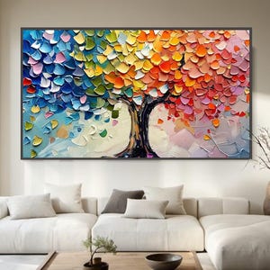 May include: Large abstract painting of a tree with a black trunk and colourful leaves. The leaves are painted in a textured style with shades of blue, green, yellow, orange, and red. The artwork is framed in a black rectangular frame.