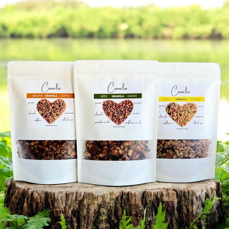 May include: Three white bags of granola with different flavors: Healthy Granola Coffee, Keto Granola Cacao, and Healthy Granola Original. Each bag has a heart-shaped logo with the ingredients listed around it.