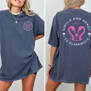 May include: A dark blue oversized t-shirt with a white graphic print that says "Single and Ready to Flamingle" with two pink flamingos and palm trees.