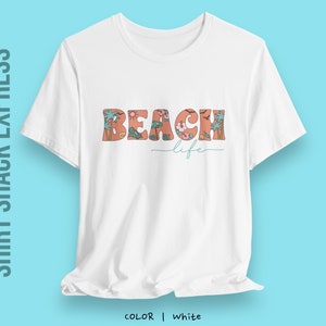 May include: White t-shirt with a floral design that spells out "Beach life" in orange letters.