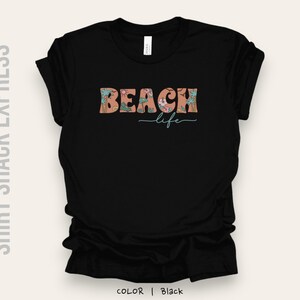 May include: Black t-shirt with a floral design and the text "Beach life" in a retro font.