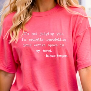 K&ouml;nnte beinhalten: Pinkes T-Shirt mit einem wei&szlig;en Aufdruck, der lautet: "Ich verurteile dich nicht. Ich renoviere heimlich deinen gesamten Raum in meinem Kopf. - Innenarchitekt"