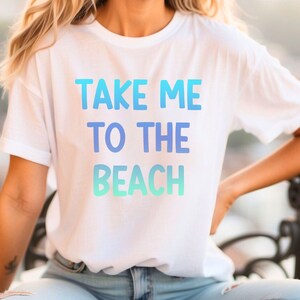 May include: A white t-shirt with a blue and green gradient print that says "TAKE ME TO THE BEACH".