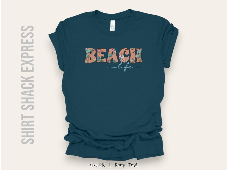 May include: A teal blue t-shirt with the text "Beach life" in a floral design. The text is in a peachy pink color with green leaves.