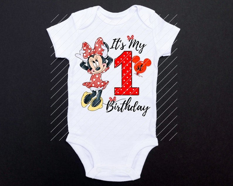 Puede incluir: Un body blanco con un personaje de Minnie Mouse rojo y negro, un n&uacute;mero uno rojo con lunares blancos y el texto "It's My 1st Birthday".