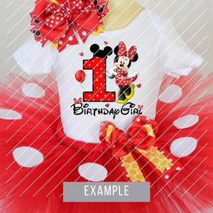 Op de afbeelding: Een witte romper met een Minnie Mouse-afbeelding, een rode tutu-rok met witte stippen en bijpassende rode strikken. De romper heeft het nummer 1 en de woorden "Birthday Girl".