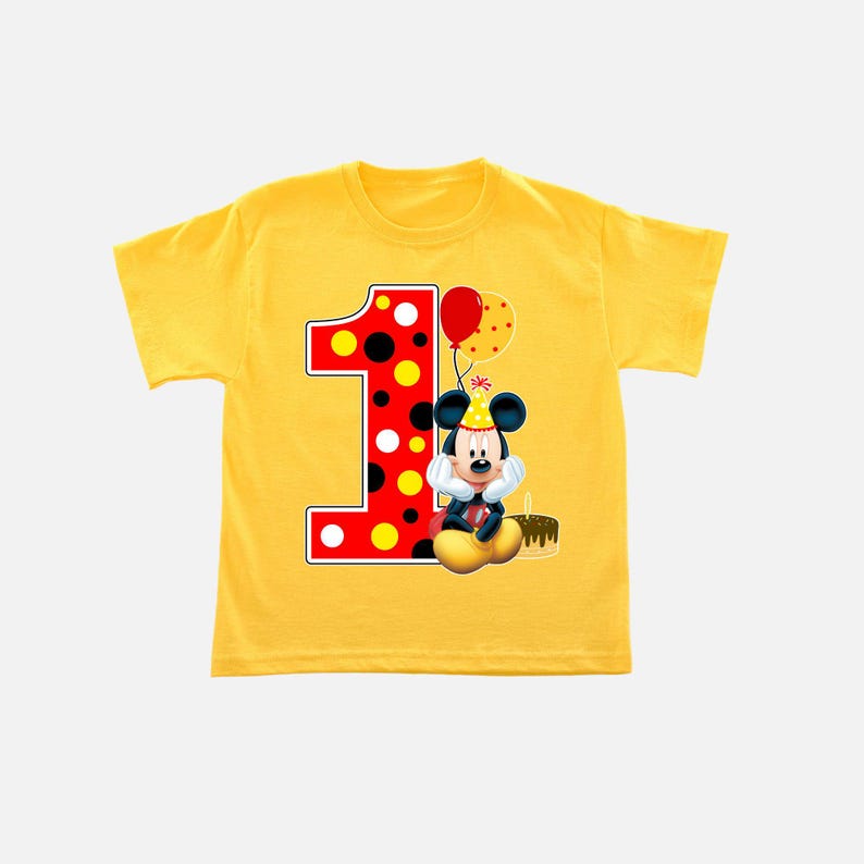K&ouml;nnte beinhalten: Gelbes T-Shirt mit einer gro&szlig;en Eins, verziert mit roten und schwarzen Punkten. Ein Cartoon-Bild von Mickey Mouse mit Partyhut befindet sich neben der Zahl, zusammen mit einem roten Ballon und einem St&uuml;ck Kuchen. Ein lustiges Geburtstags-T-Shirt.