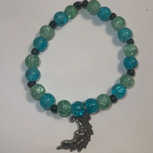 May include: A turquoise and green glass bead bracelet with a silver crescent moon charm.