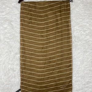 May include: A brown scarf with a pattern of diagonal white lines, hanging from a wooden hanger. The scarf has a sheer appearance and the text "MICHEL KLEIN" is visible.