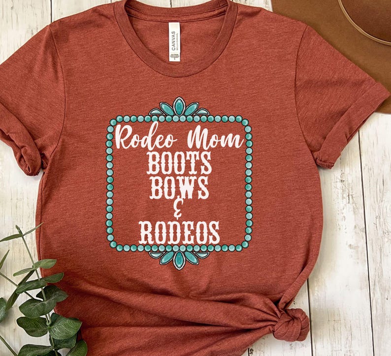 May include: A rust-colored t-shirt with a turquoise and white design that says "Rodeo Mom Boots Bows & Rodeos".