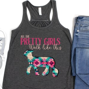 May include: A gray tank top with the text "All the Pretty Girls Walk like this" in pink lettering. A stylized image of a sheep with a pink, blue, and teal patterned design is below the text.