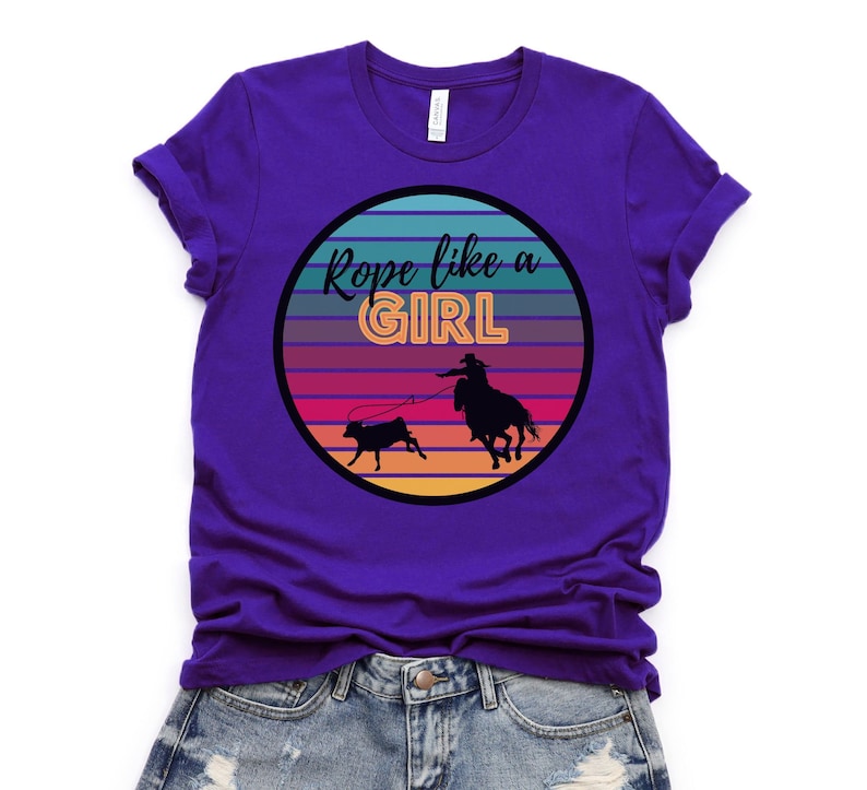 May include: Purple t-shirt with a retro sunset graphic and the text "Rope like a girl".