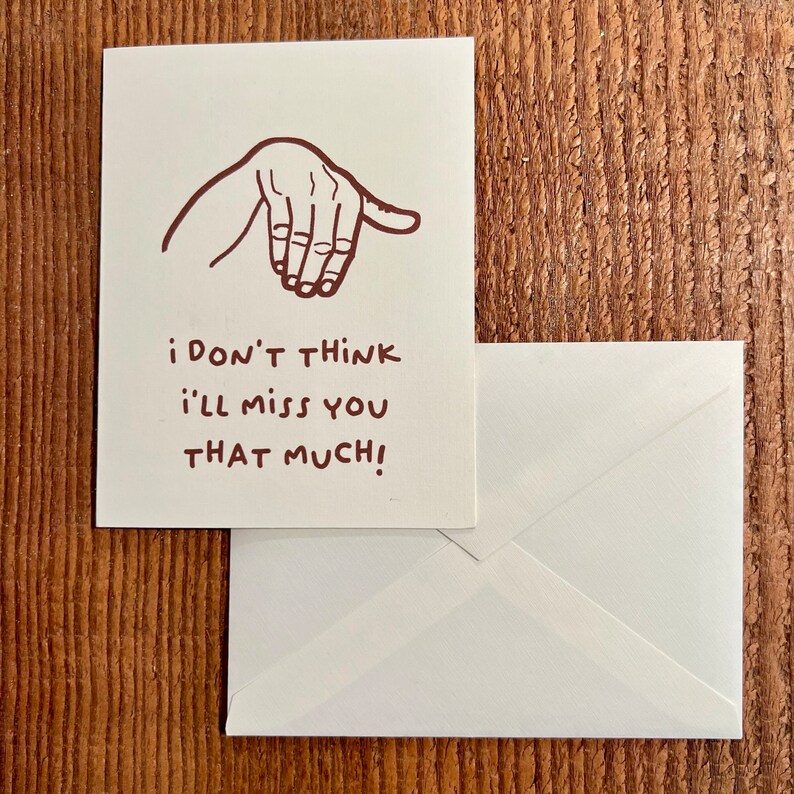 May include: A white card with a brown line drawing of a hand making a dismissive gesture. The text on the card reads "i don't think i'll miss you that much!"